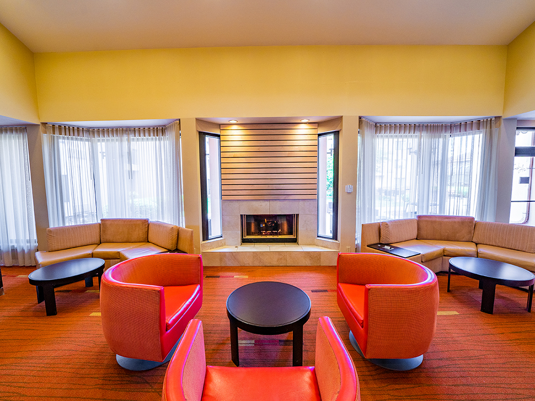 Lobby couches and chairs by a fireplace at Sonesta Select Bettendorf Quad Cities.