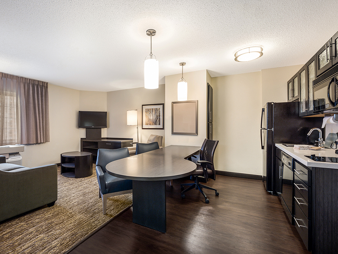 The kitchen, conference table, and living area of a One Bedroom Suite at the Sonesta Simply Suites Chicago Libertyville hotel.