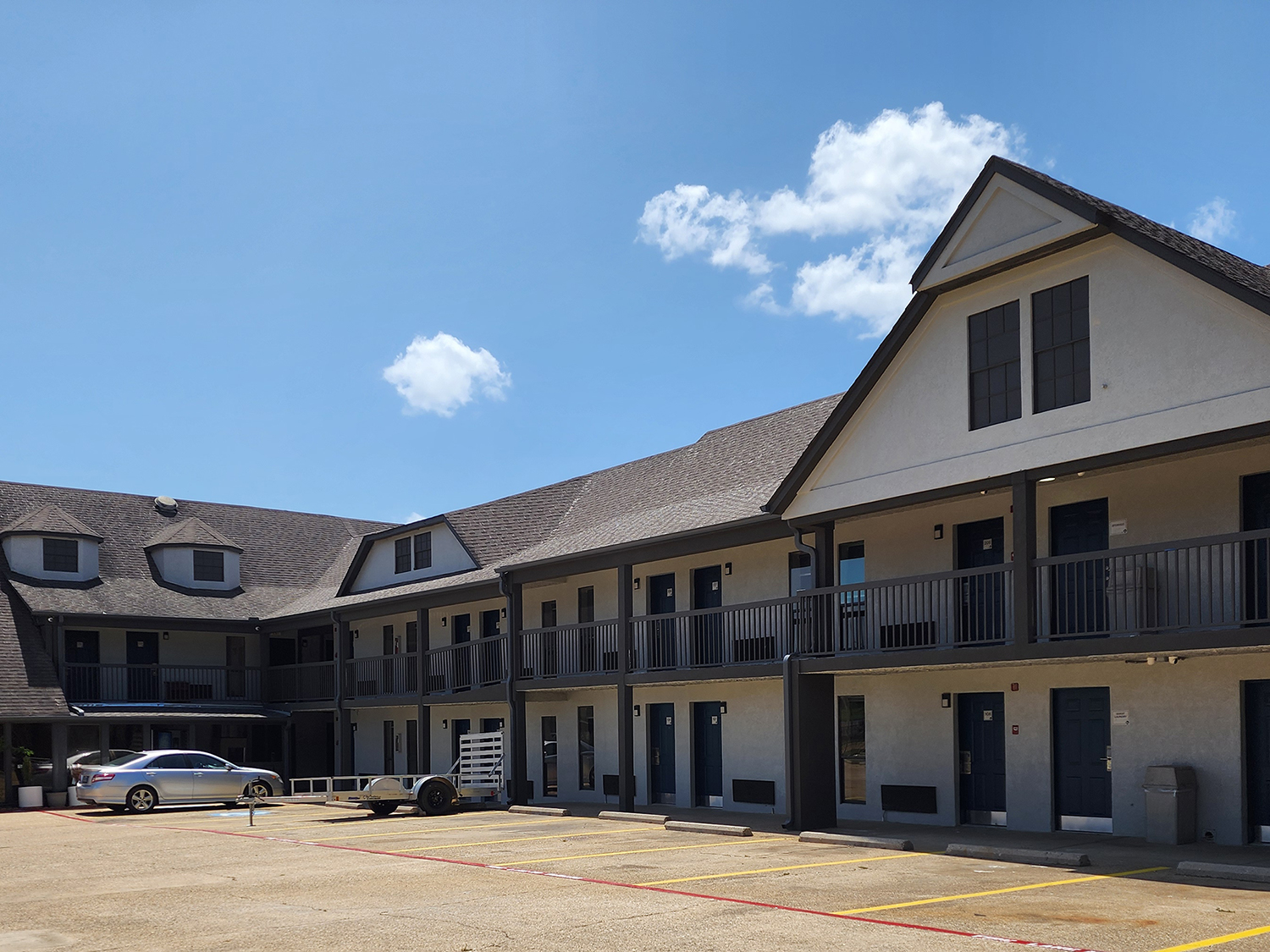 The exterior, parking lot, and guest room doors of the Americas Best Value Inn Longview hotel.