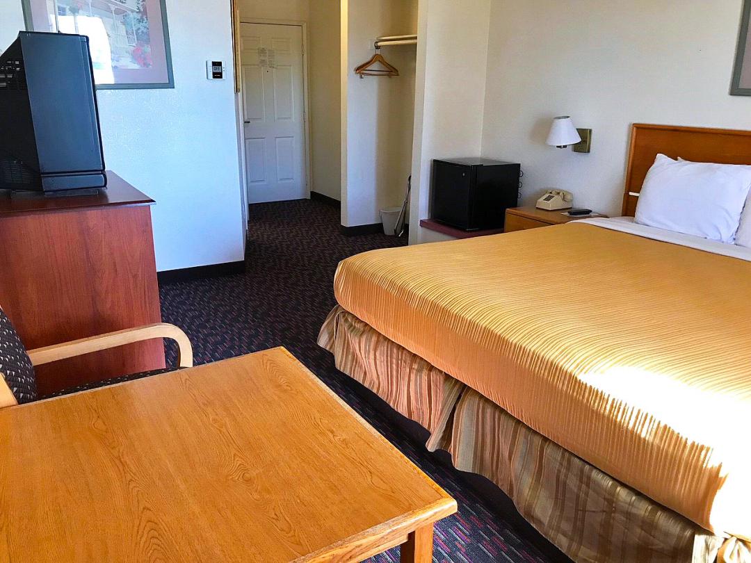 Comfortable King Bed Guest Room with a table and chairs, TV, and Micro Fridge as amenities.