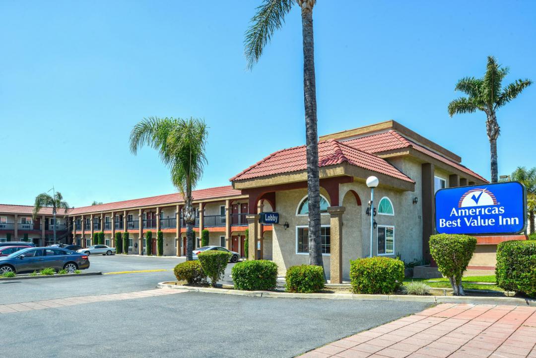 Front exterior with ample parking and palm trees on sunny day