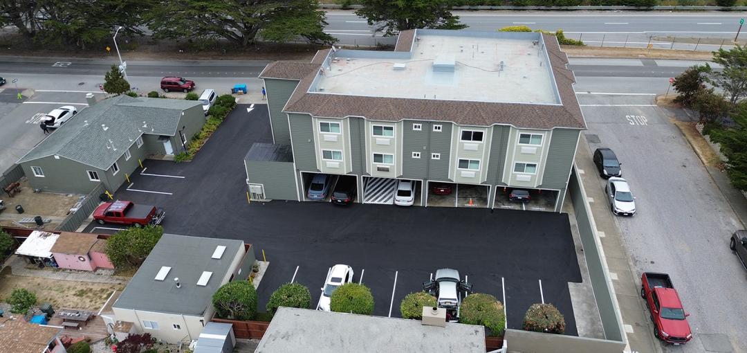 Aerial view of hotel with parking lot and surrounding area.