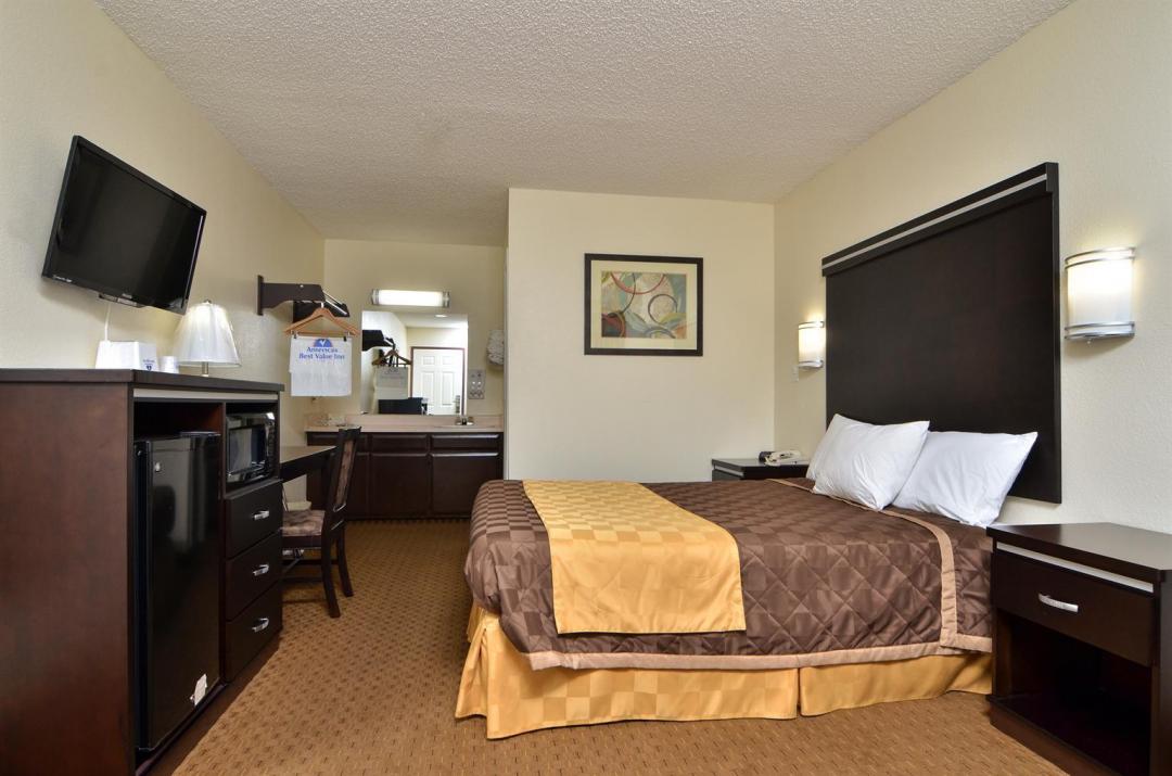 View of our Spacious One Queen Bed Guest Room with a TV, Microwave, Micro Fridge, and a Desk.