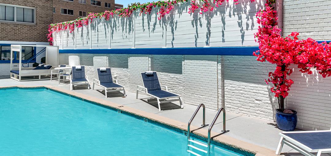Poolside lounge chairs with flowers and a brick wall