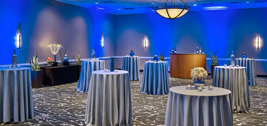Reception room with tables, chairs, and blue lighting.