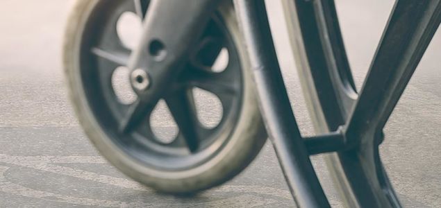 A closeup of the left wheels of a wheelchair.