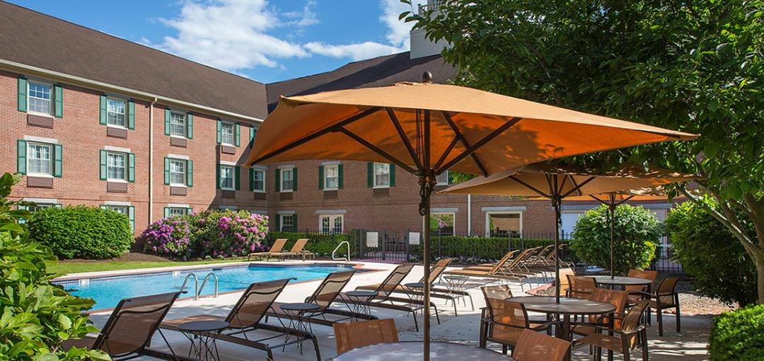 Outdoor pool area with lounge chairs, tables, and umbrellas.