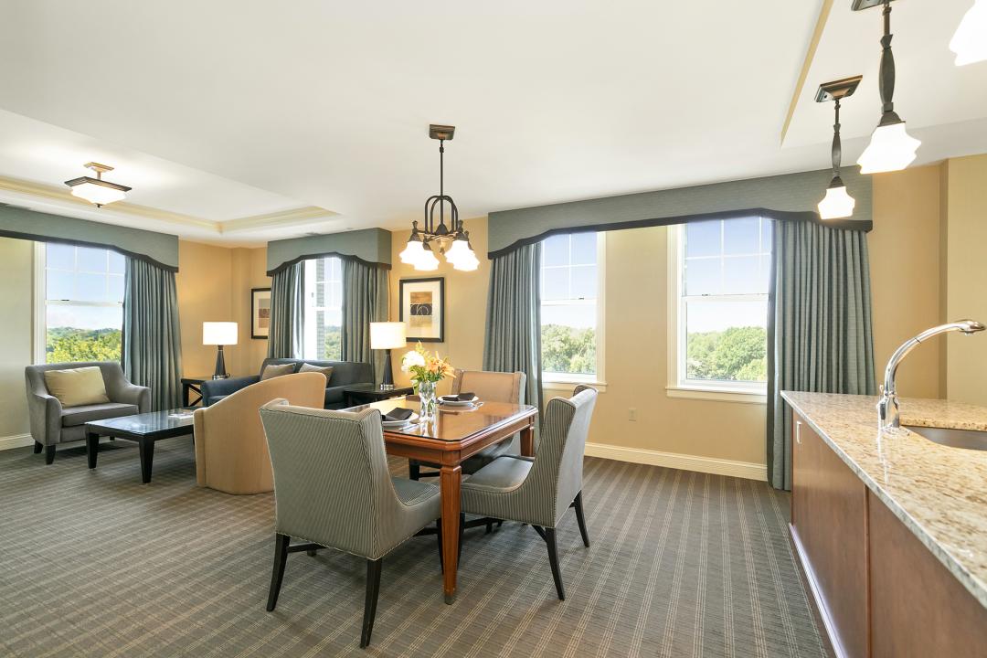 The interior of the Park Plaza Executive Apartment - King room at The Royal Sonesta Chase Park Plaza St. Louis featuring the living area with dining table, seating area with table, and sink / counter area.
