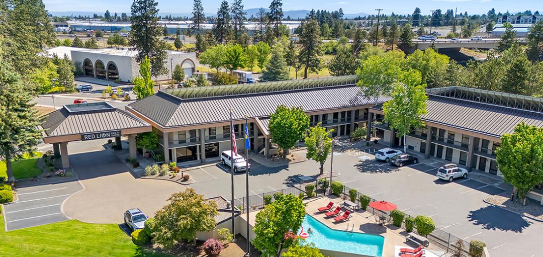 Aerial image of the pool, parking lot, and exterior of the Red Lion Inn & Suites Deschutes River Bend hotel.