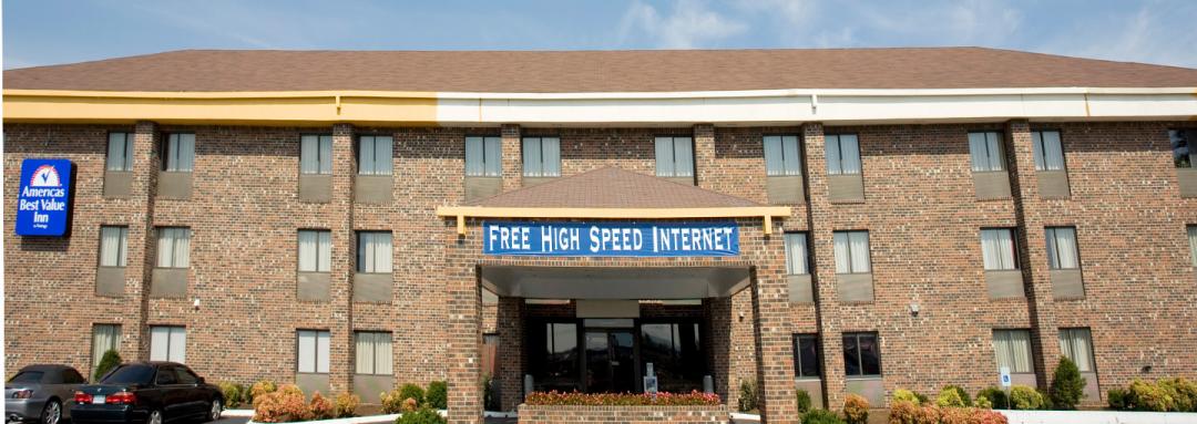 Hotel exterior with blue Free High Speed Internet sign and garden with driveway