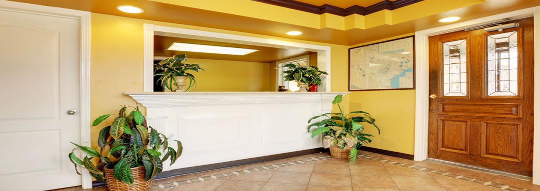 Hotel front desk and lobby with wicker basket plants and wooden doors 