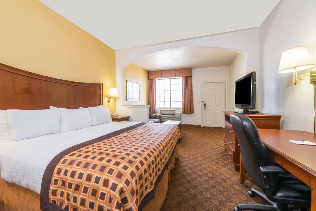 Spacious guest suite with one king bed, sofa, table, desk and chair
