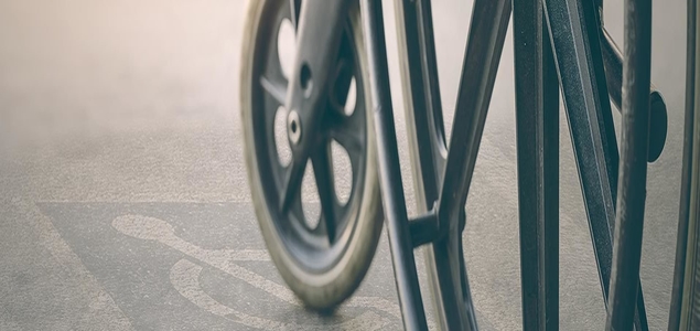 Close-up of a wheelchair wheel over an accessibility symbol.
