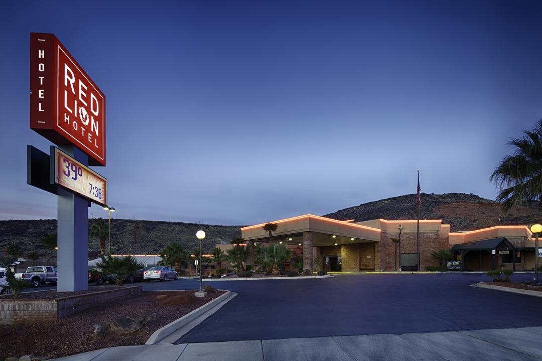 Lit up exterior with sign and hills in the background at dusk
