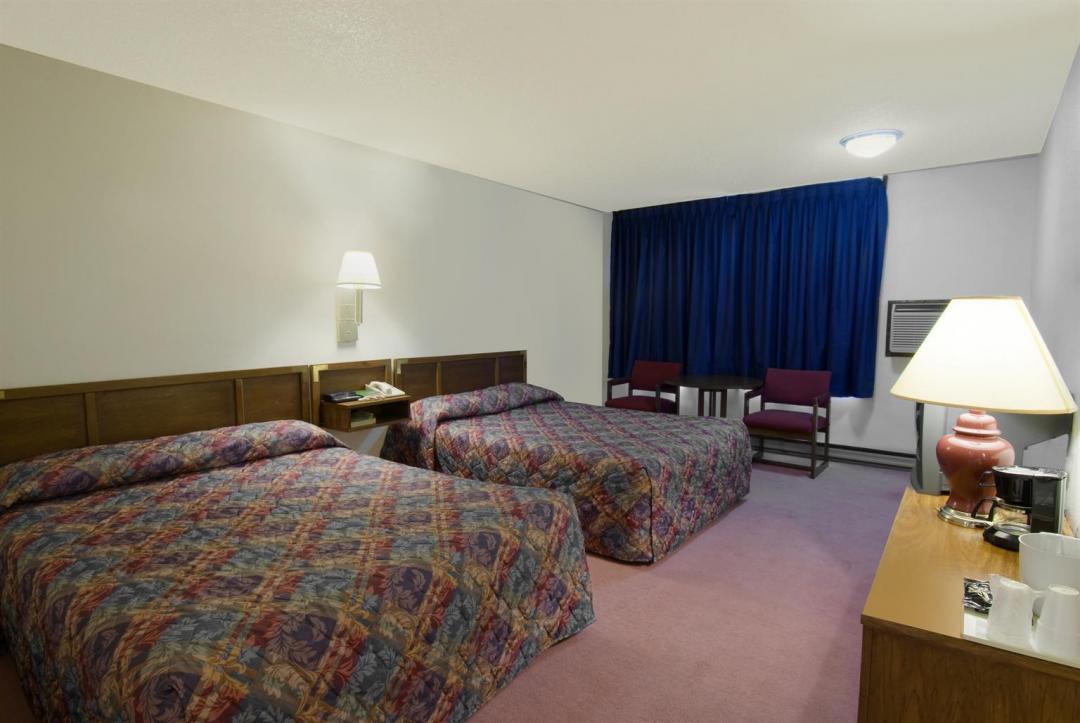 One king bed and one double bed guestroom with blue curtains, and chairs
